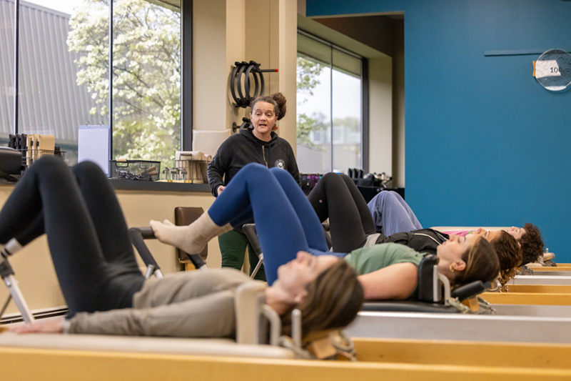 Pilates instructor teaching a group Reformer class in a Smithtown Pilates studio
