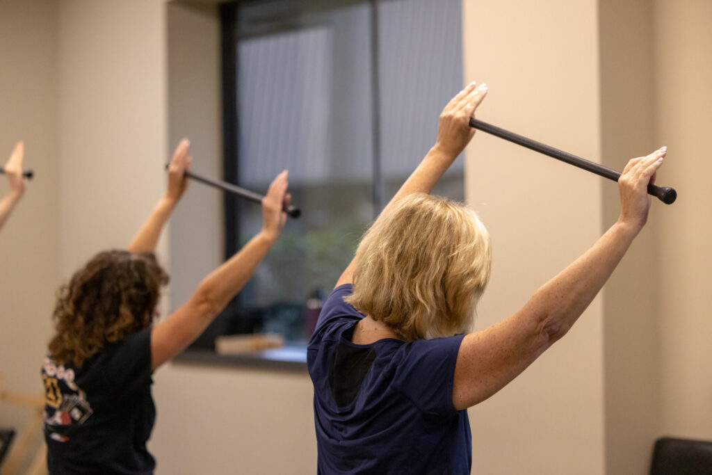 Precision Pilates studio scene showing clients exercising on reformer machines.