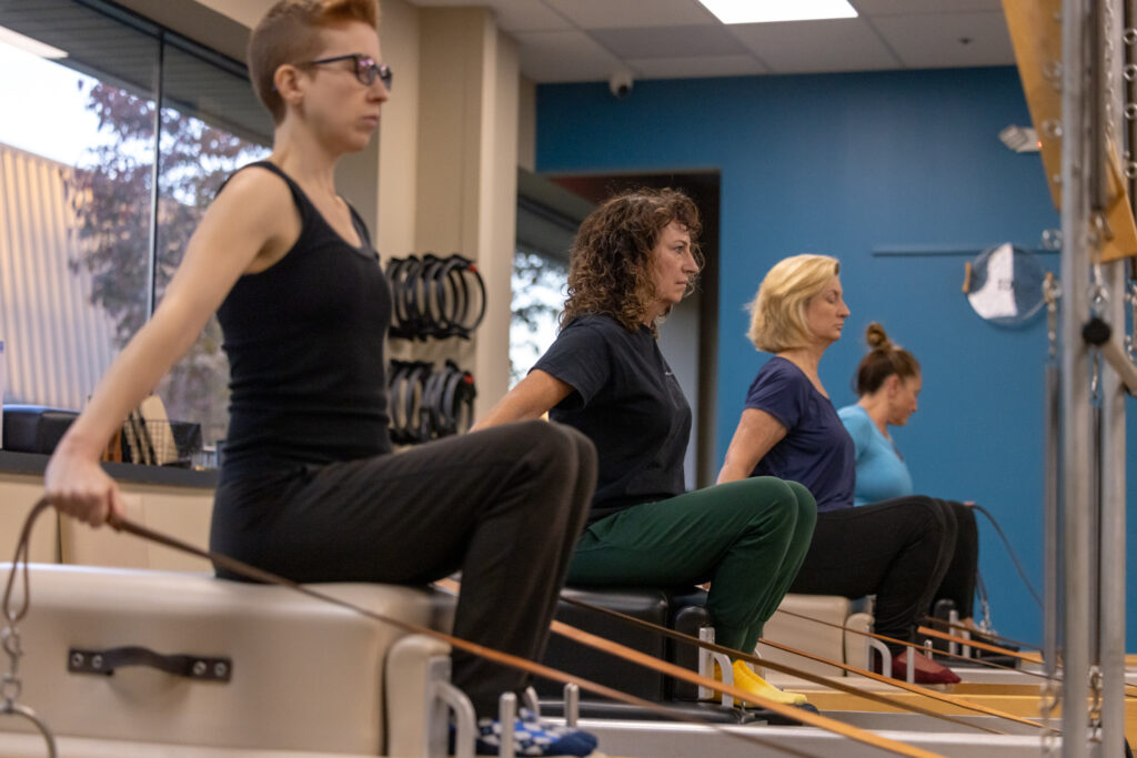 Clients using reformers to improve flexibility and posture at Precision Pilates.