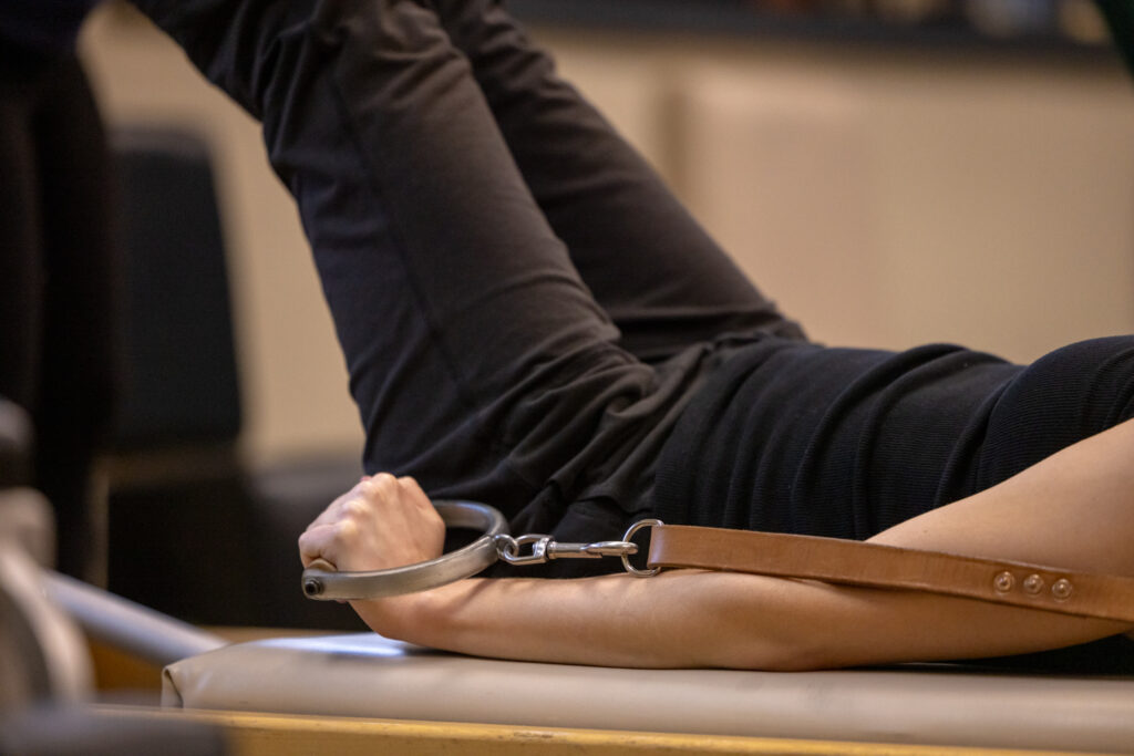 A close-up shot of a client using the Classical Reformer at Precision Pilates.